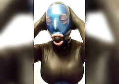 trans doll grabbing her breasts and booty in latex mask.