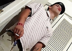 Gay stud smoking while taking his clothes off to masturbate