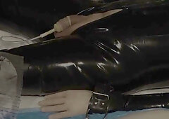 Silver latex dominatrix commands pissing and masturbation on a medical table