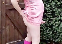 Exquisite outdoor scene featuring a sensually dressed sissy TV in captivating pink satin and boots