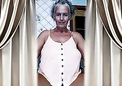 A sexy old woman sits in a kitchen chair. That babe playfully flirts with the camera, showing off her gracious aged body. Her legs are widen wide, hig