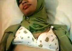 An amateur Indonesian babe, dressed in a jilbab, fingers herself in a hotel room, showcasing her Arab and Asian beauty.