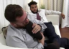 Hot hunk in stylish suit has his feet worshipped by colleague