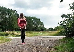 Transsexual outdoors by a busy road playing with her jock, wearing red pvc outfit